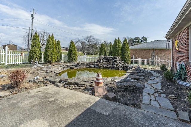 view of yard with a garden pond, a patio, and a fenced backyard