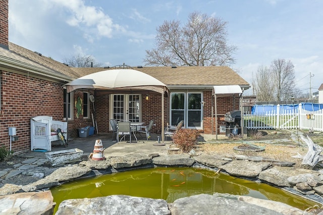 rear view of property featuring a patio, fence, french doors, and brick siding