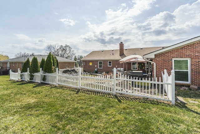 back of property with fence, a yard, a chimney, a patio area, and brick siding