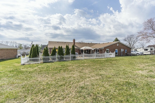 rear view of property with a chimney, a yard, and fence