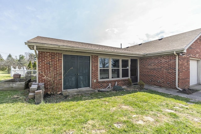 back of house featuring brick siding, an attached garage, a yard, and fence