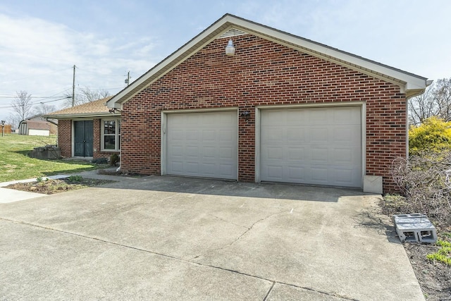 exterior space featuring a garage, brick siding, and driveway