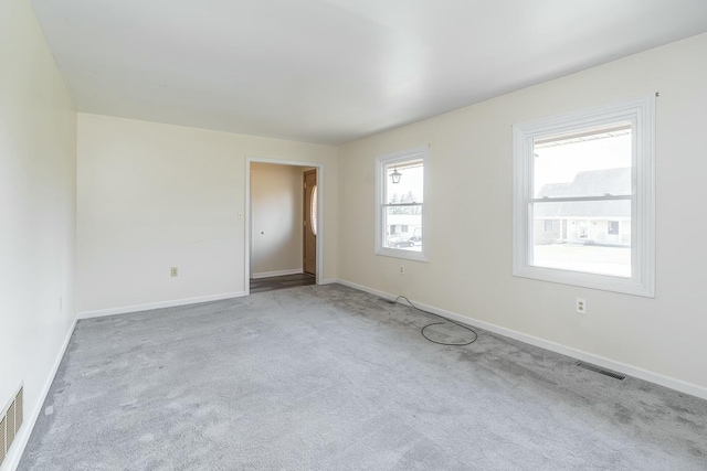 carpeted spare room with visible vents and baseboards