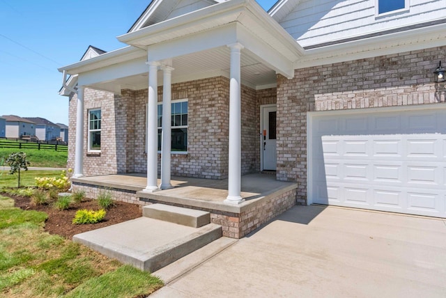 property entrance featuring fence, driveway, an attached garage, covered porch, and brick siding