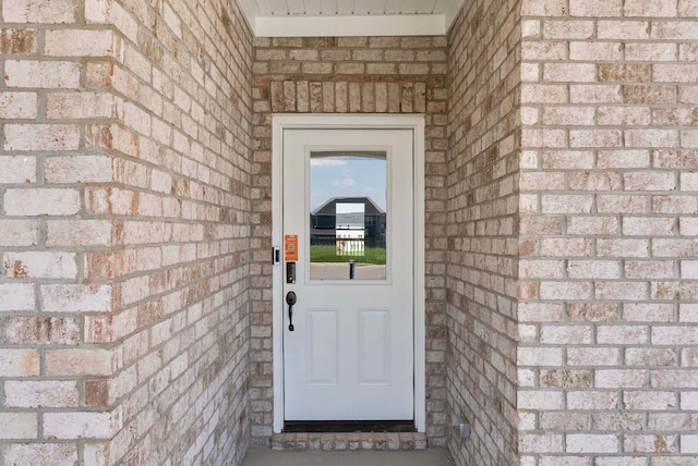 view of exterior entry featuring brick siding