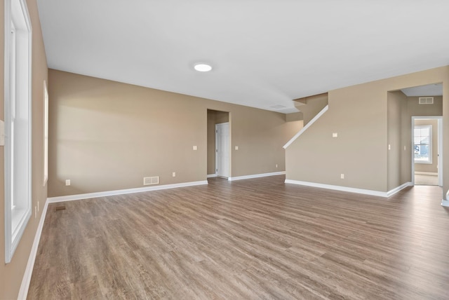 unfurnished living room with visible vents, baseboards, and wood finished floors