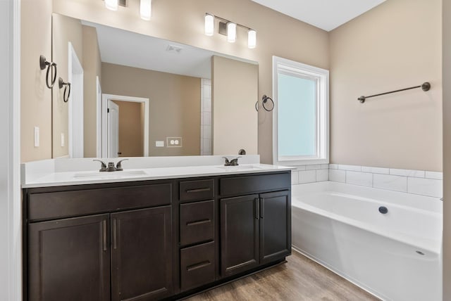 bathroom featuring a sink, a garden tub, wood finished floors, and double vanity