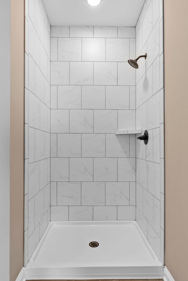 bathroom with baseboards and tiled shower