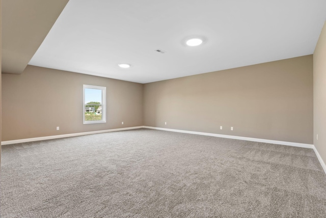 empty room with carpet flooring, visible vents, and baseboards