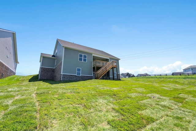 back of property with stairway, fence, a lawn, and brick siding