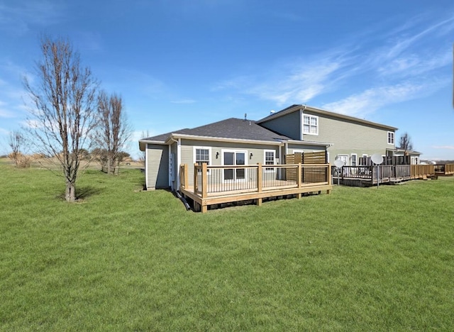 back of house featuring a yard, roof with shingles, and a wooden deck
