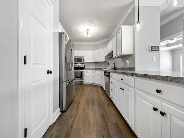 kitchen with ornamental molding, a sink, dark wood finished floors, appliances with stainless steel finishes, and white cabinets
