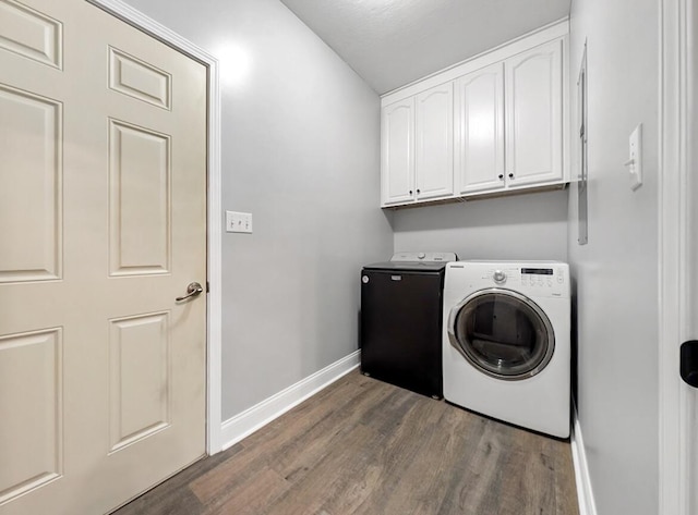 laundry area with wood finished floors, baseboards, cabinet space, and washing machine and dryer