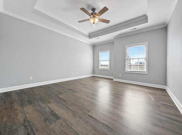 spare room with baseboards, ceiling fan, ornamental molding, a raised ceiling, and dark wood-style flooring