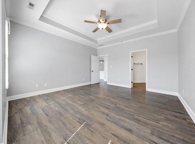 empty room featuring dark wood-style floors, a raised ceiling, and a ceiling fan