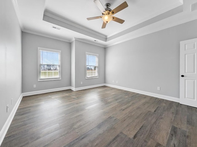 spare room with a tray ceiling, dark wood-style floors, visible vents, and baseboards