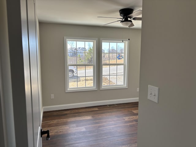 unfurnished room featuring dark wood finished floors, visible vents, baseboards, and a ceiling fan