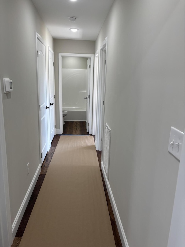 corridor featuring visible vents, dark wood-style floors, and baseboards