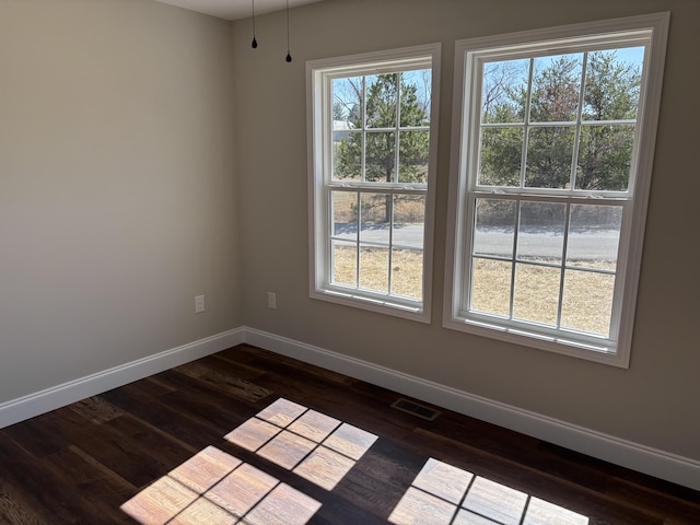 spare room with visible vents, baseboards, and dark wood-style flooring