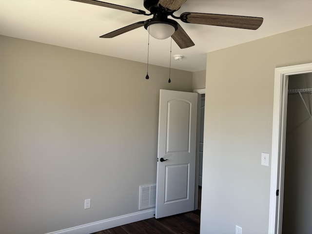 unfurnished bedroom with dark wood-style floors, visible vents, ceiling fan, and baseboards