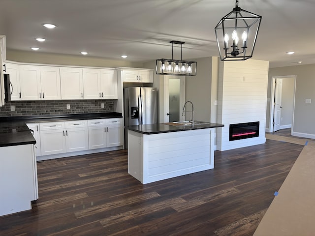 kitchen featuring dark countertops, stainless steel fridge with ice dispenser, dark wood-style flooring, and a sink