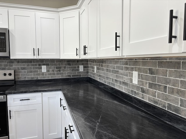 kitchen with tasteful backsplash, white cabinets, stainless steel appliances, and dark stone countertops