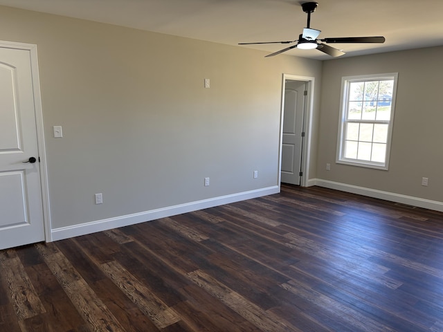 spare room with baseboards, dark wood-type flooring, and a ceiling fan