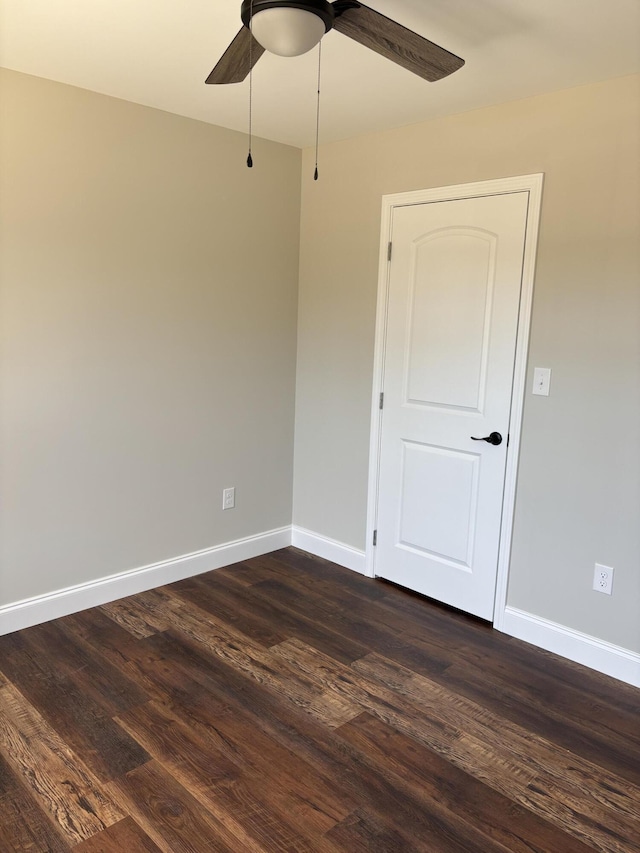 spare room with baseboards, dark wood-type flooring, and ceiling fan