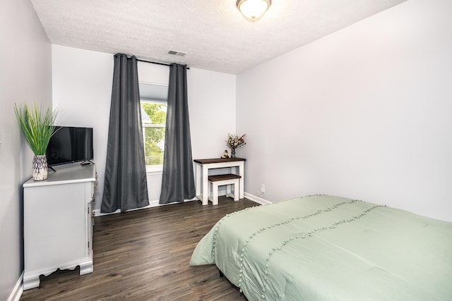 bedroom featuring visible vents, baseboards, dark wood-type flooring, and a textured ceiling