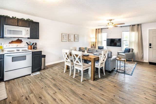 kitchen with white appliances, a ceiling fan, light countertops, light wood-style floors, and open floor plan