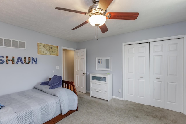 carpeted bedroom featuring baseboards, visible vents, ceiling fan, a closet, and a textured ceiling