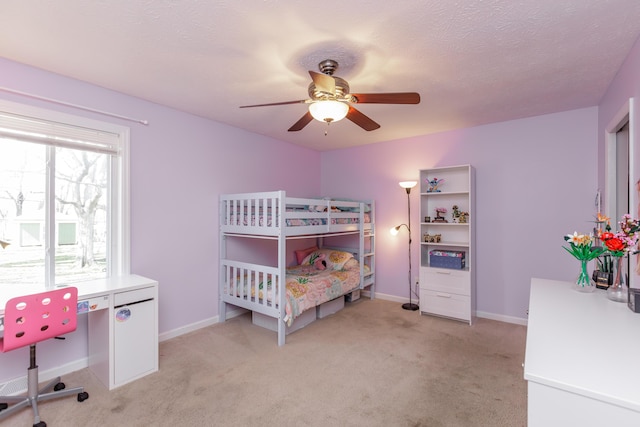 bedroom featuring a textured ceiling, light colored carpet, baseboards, and ceiling fan