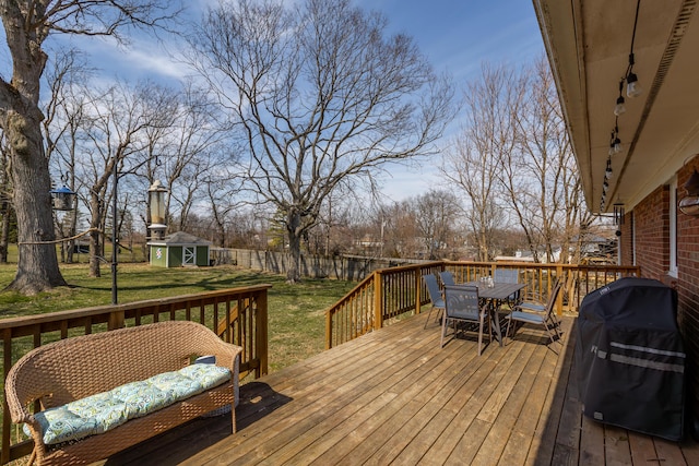 deck featuring outdoor dining space, a shed, area for grilling, a yard, and an outdoor structure