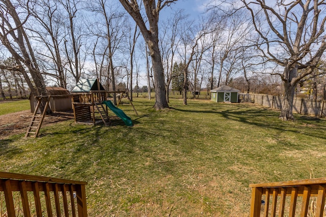 view of yard with a playground, fence, an outdoor structure, and a shed