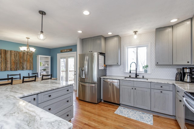 kitchen with light wood-style floors, gray cabinets, appliances with stainless steel finishes, and a sink