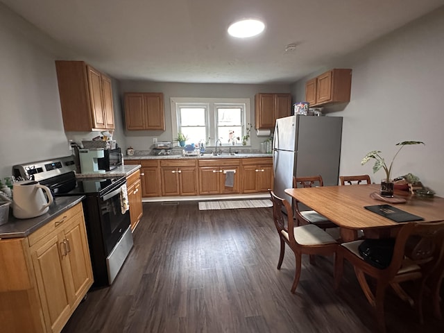 kitchen featuring brown cabinets, range with electric cooktop, a sink, dark wood finished floors, and freestanding refrigerator