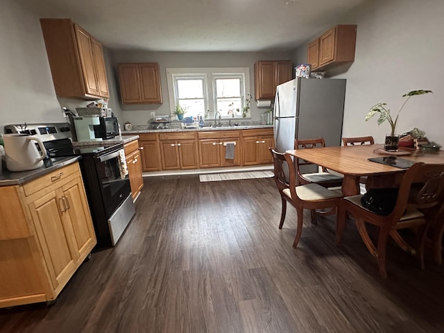 kitchen with brown cabinets, range with electric stovetop, freestanding refrigerator, dark wood-style floors, and a sink