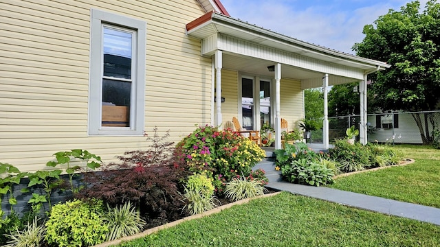 entrance to property featuring covered porch and a yard