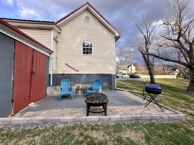 rear view of property featuring a lawn, an outdoor fire pit, and a patio