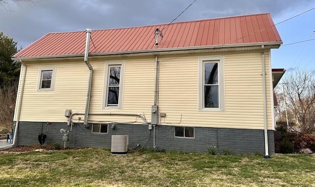 view of home's exterior featuring a lawn, metal roof, and central AC