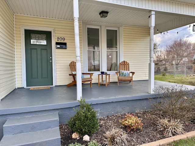 doorway to property featuring fence and covered porch