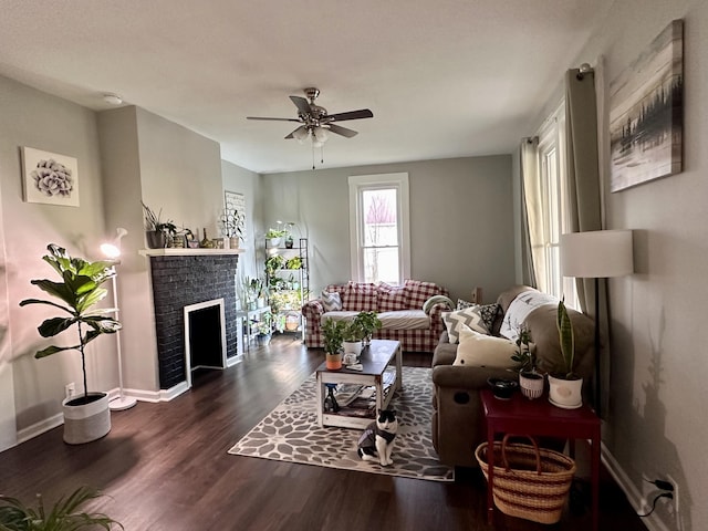 living room featuring a ceiling fan, a brick fireplace, wood finished floors, and baseboards