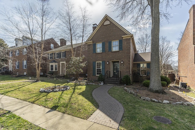 view of front of house featuring a front yard, central air condition unit, brick siding, and a chimney