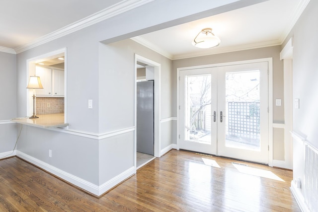 interior space featuring wood finished floors, crown molding, a healthy amount of sunlight, and french doors