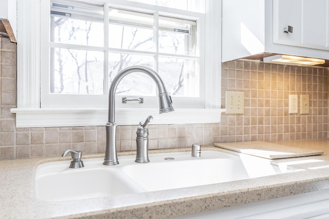 details with white cabinets, light stone countertops, backsplash, and a sink