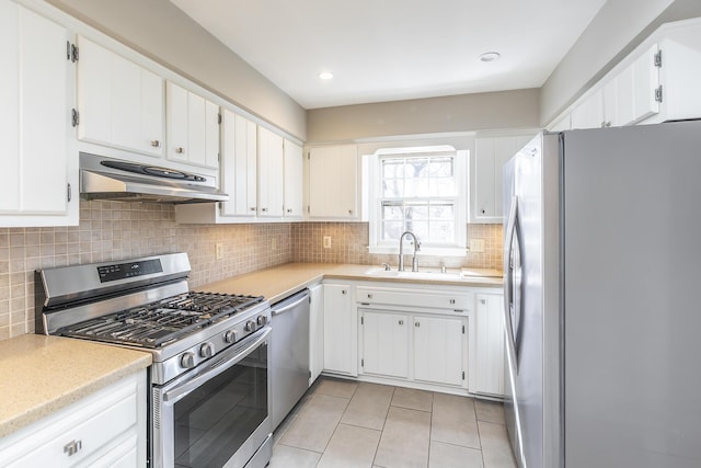 kitchen featuring under cabinet range hood, a sink, backsplash, appliances with stainless steel finishes, and light countertops