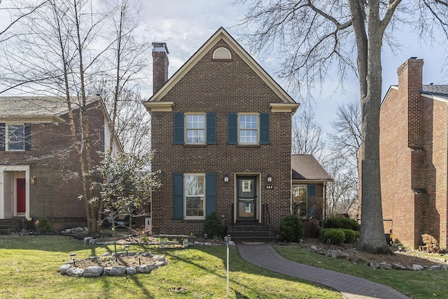 traditional-style home with brick siding, a chimney, and a front lawn