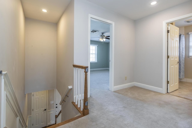 hall with an upstairs landing, carpet flooring, baseboards, and visible vents