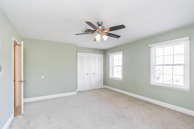 unfurnished bedroom with a ceiling fan, light colored carpet, baseboards, and a closet