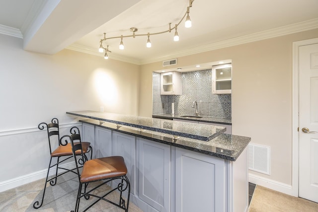 kitchen with glass insert cabinets, visible vents, backsplash, and ornamental molding